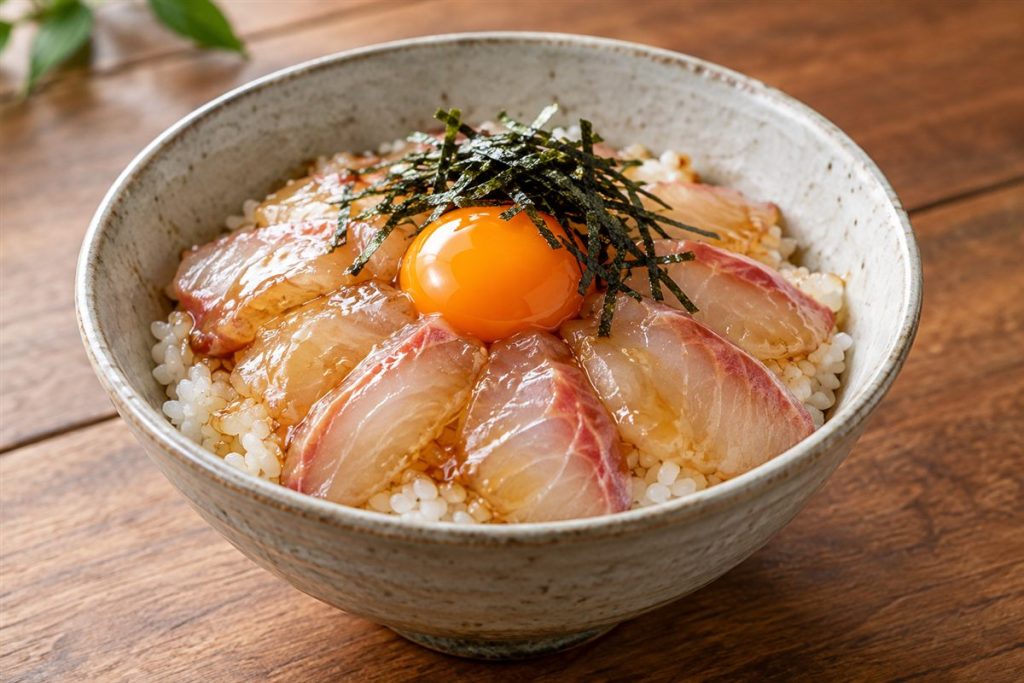 白飯の上にタレをまとった鯛の切り身と卵黄、刻みのりをのせた丼