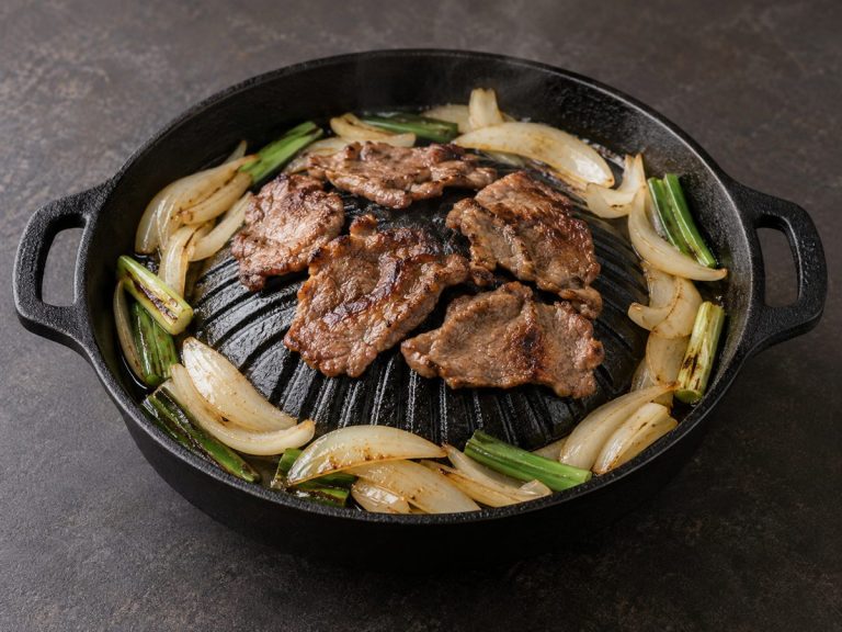 鉄板に並べた肉と玉ねぎ、長ねぎ
